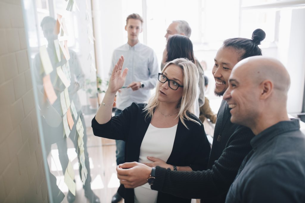 Smiling business team looking at adhesive notes in board room during meeting